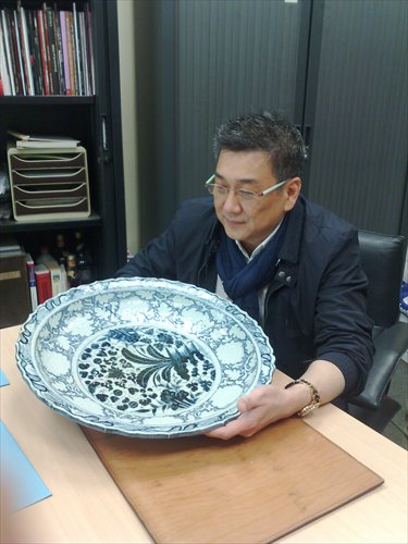 Preeminent dealer William Chak appreciates a blue and white Yuan Dynasty (1279-1368) ashet at a 2011 pre-auction exhibition. Photo: Courtesy of Chak's Company Limited