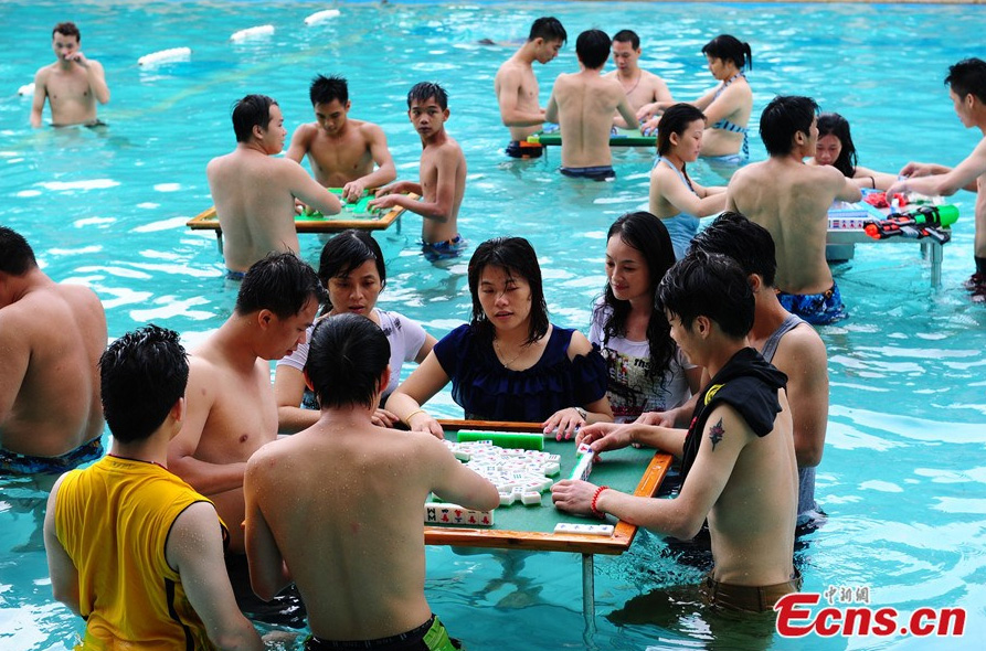 Players compete in a match during a mahjong contest held in a swimming pool at a scenic spot in Foshan, Guangdong province on June 24, 2014. Organized by Jiudaogu Rafting, an ecotourism spot in the Players compete in a match during a mahjong contest held in a swimming pool at a scenic spot in Foshan, Guangdong province on June 24, 2014. [Photo/Ecns.cn]