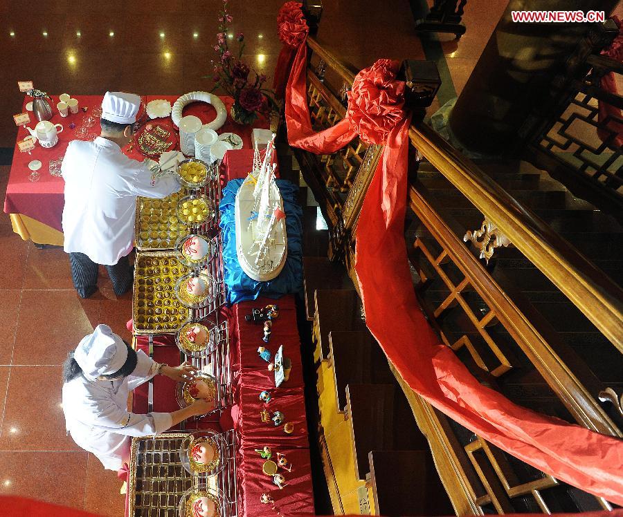 Staff members are busy arranging showcase for a ceremony for the 150th anniversary of Quanjude Beijing Roast Duck Restaurant at its Qianmen Branch in Beijing, capital of China, July 2, 2014. [Photo/Xinhua]