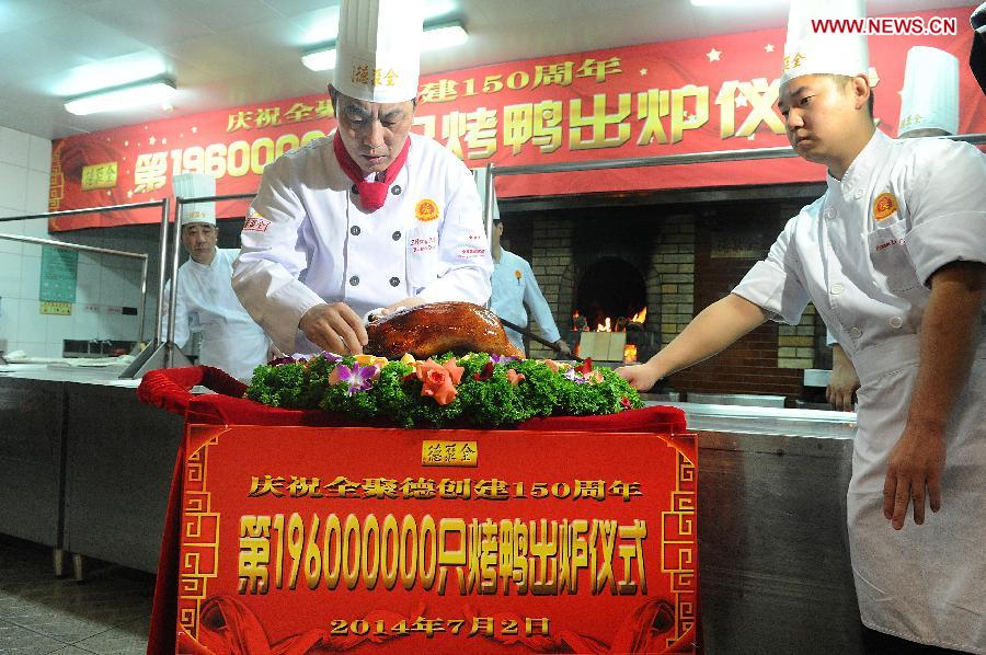 Head chef Zheng Zhiqiang places Quanjude's 196 millionth roast duck on a plate during a ceremony for the 150th anniversary of Quanjude Beijing Roast Duck Restaurant at its Qianmen Branch in Beijing, capital of China, July 2, 2014. [Photo/Xinhua]