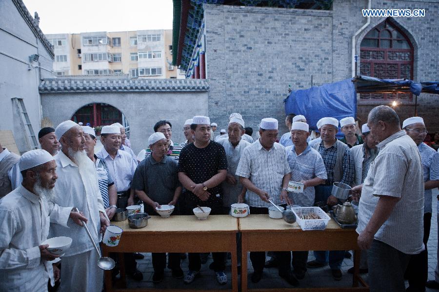 Muslims wait to break their fast at the Qingzhenzhongsi Mosque in Yinchuan, capital of Ningxia Hui Autonomous Region, July 3, 2014. Built in 1931, the mosque was located in downtown Yinchuan and known for its ancient-style architectures. [Photo/Xinhua]