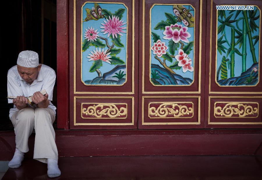 A Muslim reads scriptures at the Qingzhenzhongsi Mosque in Yinchuan, capital of Ningxia Hui Autonomous Region, July 3, 2014. Built in 1931, the mosque was located in downtown Yinchuan and known for its ancient-style architectures. [Photo/Xinhua]
