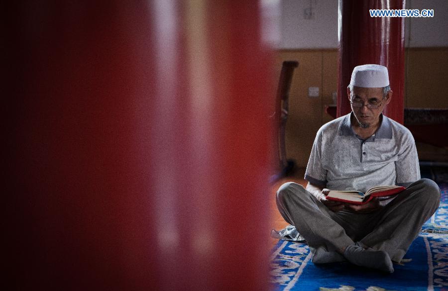 A Muslim reads scriptures at the Qingzhenzhongsi Mosque in Yinchuan, capital of Ningxia Hui Autonomous Region, July 3, 2014. Built in 1931, the mosque was located in downtown Yinchuan and known for its ancient-style architectures. [Photo/Xinhua]