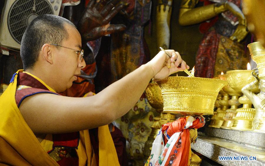 The 11th Panchen Lama Bainqen Erdini Qoigyijabu, who is also a member of the Standing Committee of the Chinese People's Political Consultative Conference (CPPCC) National Committee, lights a lamp for a Buddha statue at the Jokhang Temple in Lhasa, capital of southwest China's Tibet Autonomous Region, July 2, 2014. The Panchen Lama made a research and inspection tour in Lhasa in recent days. [Photo/Xinhua]