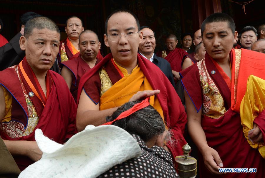 The 11th Panchen Lama Bainqen Erdini Qoigyijabu (C), who is also a member of the Standing Committee of the Chinese People's Political Consultative Conference (CPPCC) National Committee, offers head-touching blessings to Buddhist believers at the Sera Monastery in Lhasa, capital of southwest China's Tibet Autonomous Region, July 3, 2014. The Panchen Lama made a research and inspection tour in Lhasa in recent days. [Photo/Xinhua]