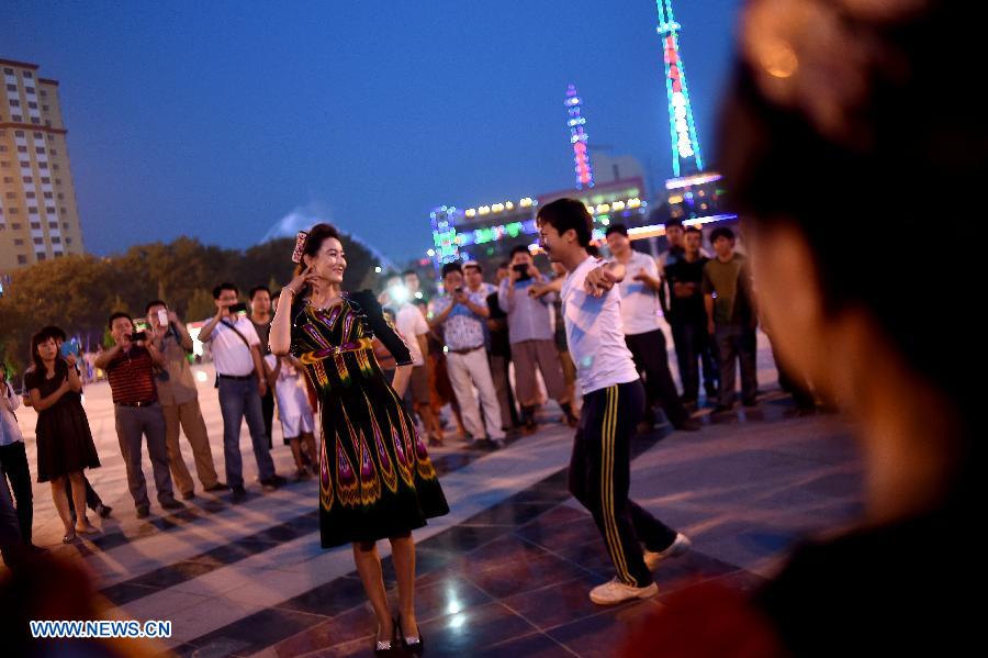 Citizens dance at the Maigaiti Dolan Culture Square in Maigaiti County, northwest China's Xingjiang Uygur Autonomous Region, June 29, 2014. Maigaiti County, known as the 'home of Dolan', has taken measures to protect and inherit the world intangible cultural heritage 'Dolan Muqam' since April 2012. [Photo/Xinhua]