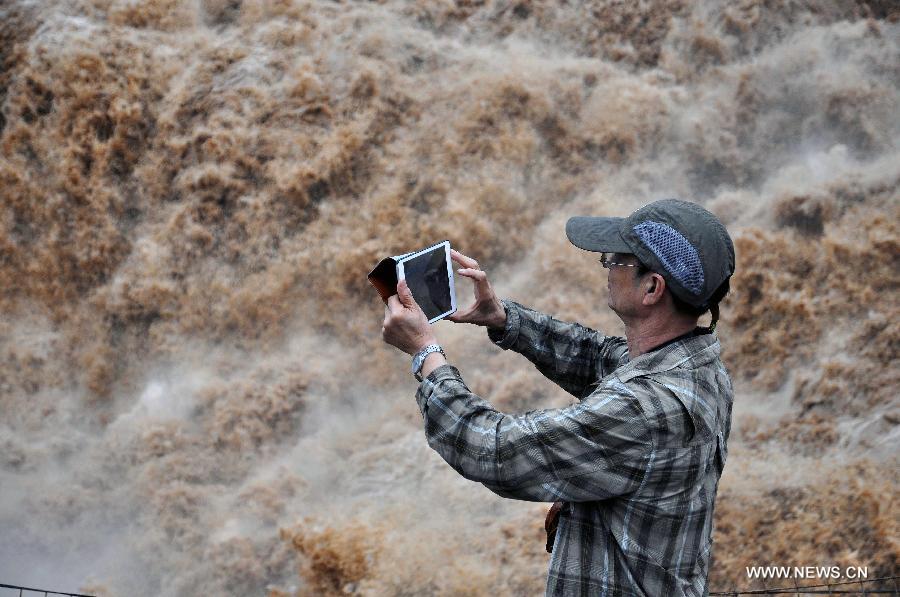 A tourist takes photos of the Hukou Waterfall of the Yellow River, north China's Shanxi Province, July 9, 2014. [Photo/Xinhua]