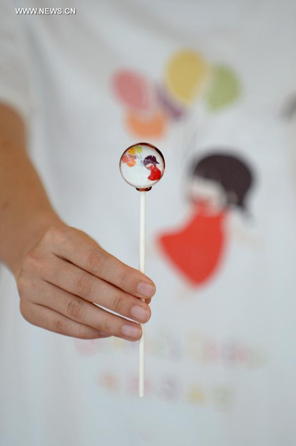 A staff of a local bakery demonstrates a customized lolipop in Shenyang, capital of northeast China's Liaoning Province, July 9, 2014. [Photo/Xinhua]