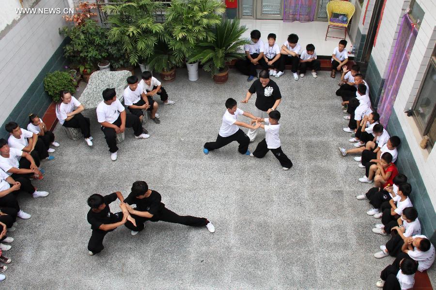 Students learn to play Tai Chi in Wenxian County of Jiaozuo City, central China's Henan Province, July 8, 2014. Many primary and middle school students in Wenxian took part in Tai Chi training classes during the summer vacation. [Photo/Xinhua]