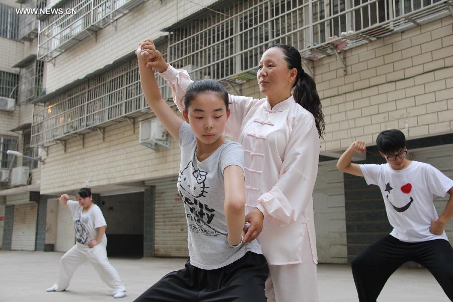 A teacher instructs a student in playing Tai Chi in Wenxian County of Jiaozuo City, central China's Henan Province, July 9, 2014. Many primary and middle school students in Wenxian took part in Tai Chi training classes during the summer vacation. [Photo/Xinhua]
