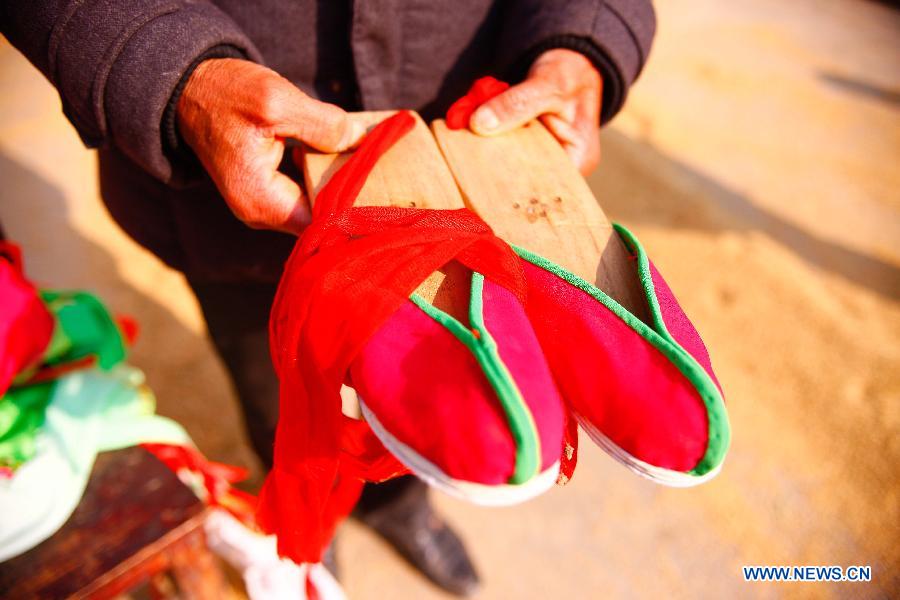 Flower Drum Dance performer Shi Chuncai displays his his performing shoes in Lianhua Village, Huaiyuan County of Bengbu City, east China's Anhui Province, Dec 3, 2014. [Photo/Xinhua]
