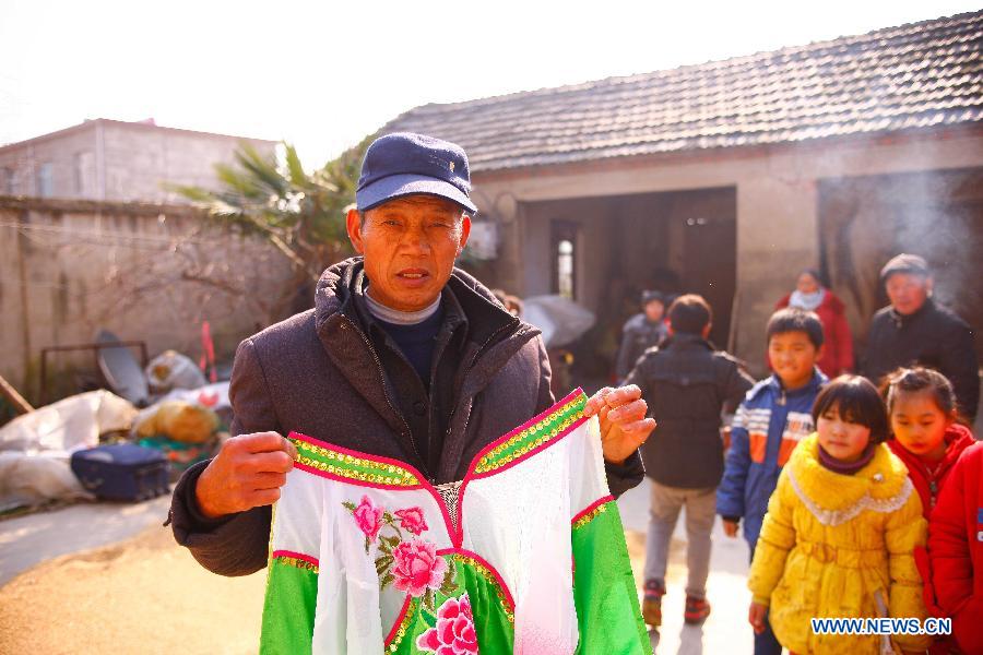 Flower Drum Dance performer Shi Chuncai displays his costume at home in Lianhua Village, Huaiyuan County of Bengbu City, east China's Anhui Province, Dec 3, 2014. [Photo/Xinhua]