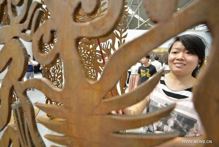 Audience look at a sculpture by Chinese artist Ren Rong during the 1st Xinjiang International Art Biennale in Urumqi, capital of northwest China's Xinjiang Uygur Autonomous Region, June 25, 2014. Hundreds of artworks by 132 artists from 18 countries were presented during the biennale. [Photo/Xinhua]