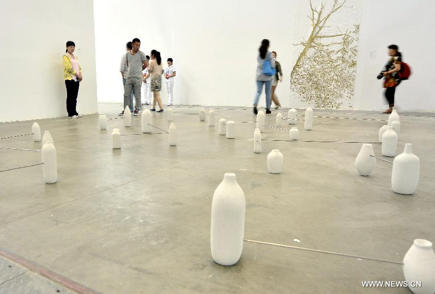 Audience watch an artwork during the 1st Xinjiang International Art Biennale in Urumqi, capital of northwest China's Xinjiang Uygur Autonomous Region, June 25, 2014. Hundreds of artworks by 132 artists from 18 countries were presented during the biennale. [Photo/Xinhua]