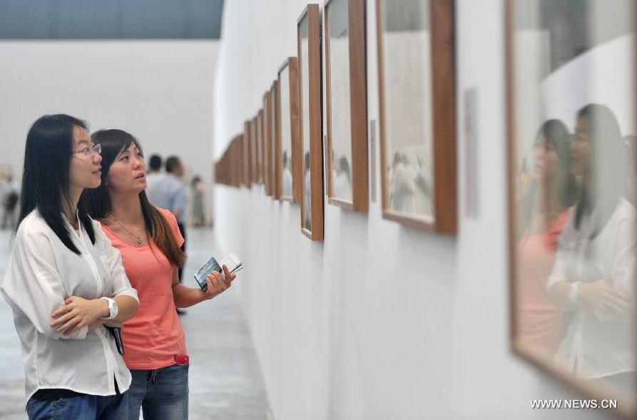 Audience watch artworks during the 1st Xinjiang International Art Biennale in Urumqi, capital of northwest China's Xinjiang Uygur Autonomous Region, June 25, 2014. Hundreds of artworks by 132 artists from 18 countries were presented during the biennale. [Photo/Xinhua]