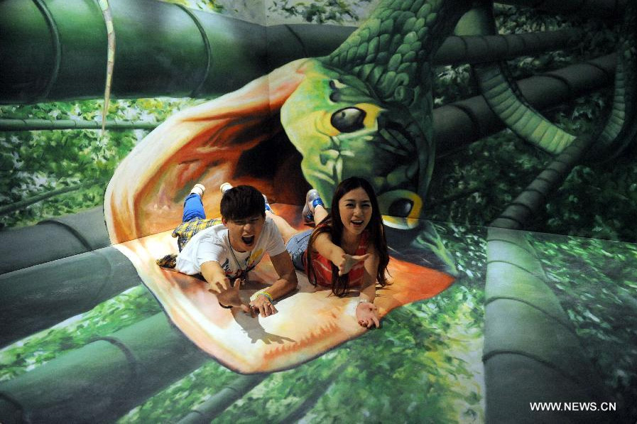 Visitors pose for a photo with a 3D image at the HK 3D Museum in Hong Kong, south China, June 26, 2014. The 3D art museum, the first of this kind in Hong Kong, was unveiled here on Thursday. [Photo/Xinhua]
