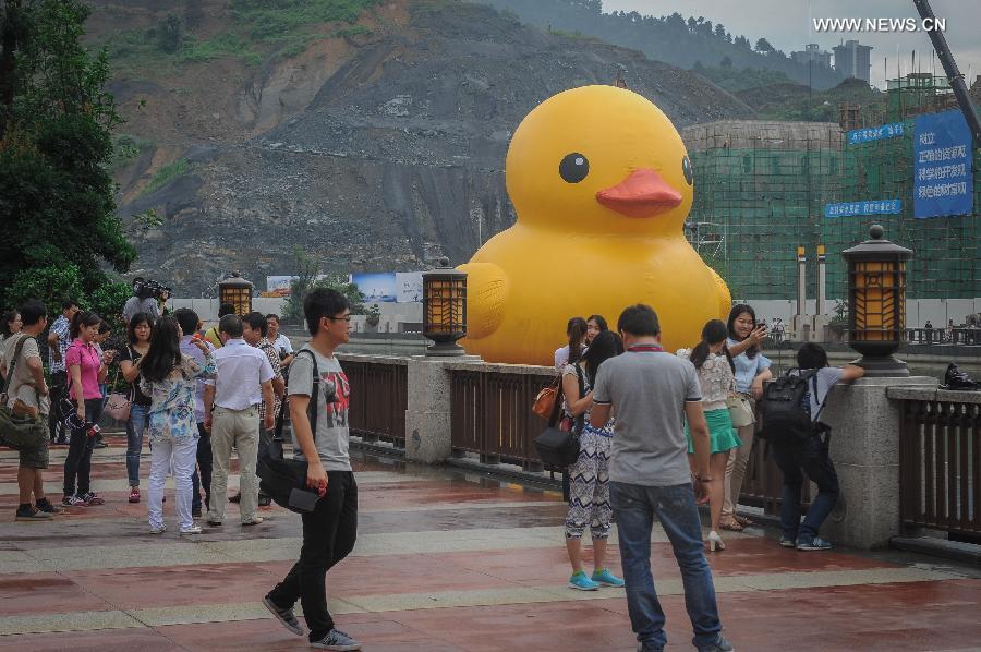 Residents gather to watch a giant yellow rubber duck floating on Nanming River in Guiyang, capital of southwest China's Guizhou Province, July 3, 2014. The 18-meter-tall rubber duck, brainchild of Dutch artist Florentijn Hofman, will berth in Guiyang from July 4 to August 24. [Photo/Xinhua]