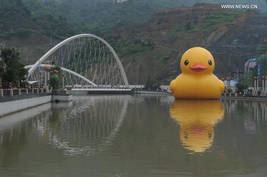A giant yellow rubber duck floats on Nanming River in Guiyang, capital of southwest China's Guizhou Province, July 3, 2014. The 18-meter-tall rubber duck, brainchild of Dutch artist Florentijn Hofman, will berth in Guiyang from July 4 to August 24. [Photo/Xinhua]