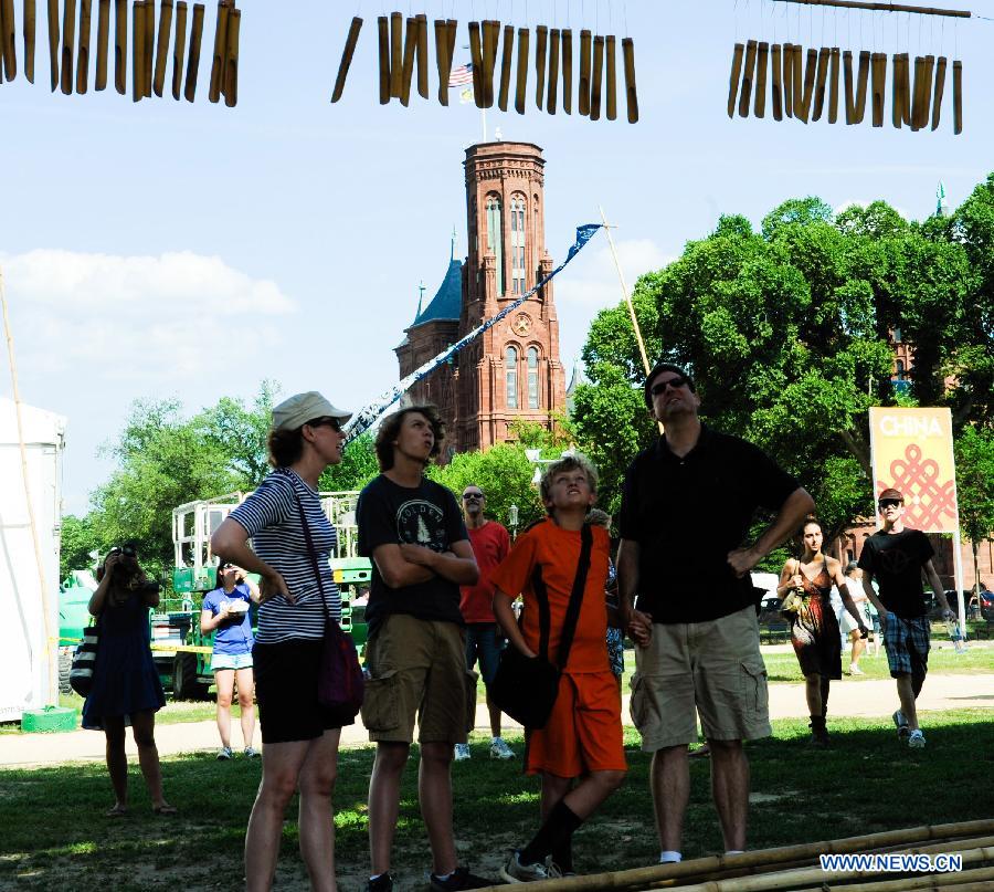 A group of visitors watch the wind chimes hanging on the Flower Plaque during the 48th Smithsonian Folklife Festival in Washington D.C., capital of the United States, July 6, 2014. The 48th annual Smithsonian Folklife Festival closed in Washington on Sunday. [Photo/Xinhua]
