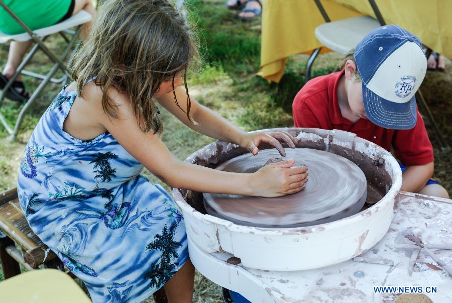 A girl plays with porcelain clay during the 48th Smithsonian Folklife Festival in Washington D.C., capital of the United States, July 6, 2014.The 48th annual Smithsonian Folklife Festival closed in Washington on Sunday. [Photo/Xinhua]
