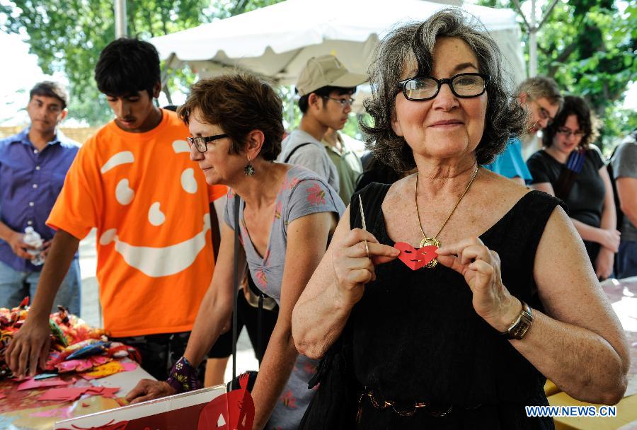 A visitor shows her papercutting work during the 48th Smithsonian Folklife Festival in Washington D.C., capital of the United States, July 6, 2014. The 48th annual Smithsonian Folklife Festival closed in Washington on Sunday. [Photo/Xinhua]
