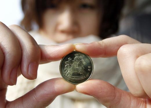 A resident shows the 1-yuan commemorative coin marking the coming Year of the Horse on Tuesday morning.