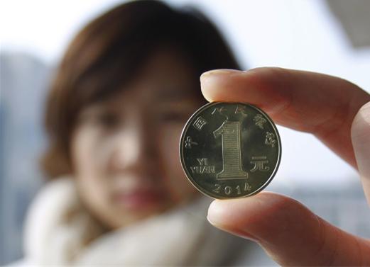 A resident shows the 1-yuan commemorative coin marking the coming Year of the Horse on Yuesday morning.